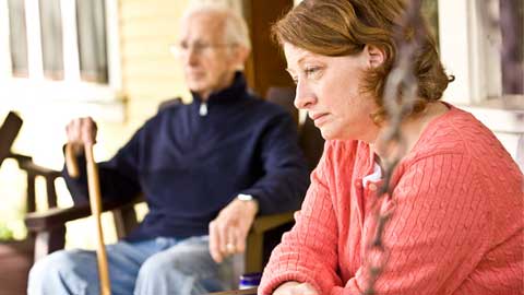 Family caregiver looking tired while sitting with senior loved one